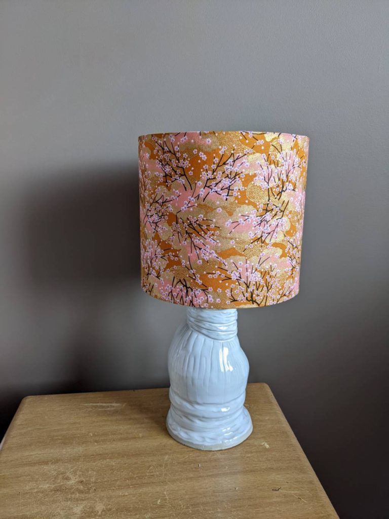 Pottery lamp with Japanese fabric shade in daytime light.