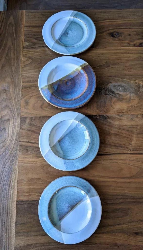 A row of pottery plates on a wooden table.