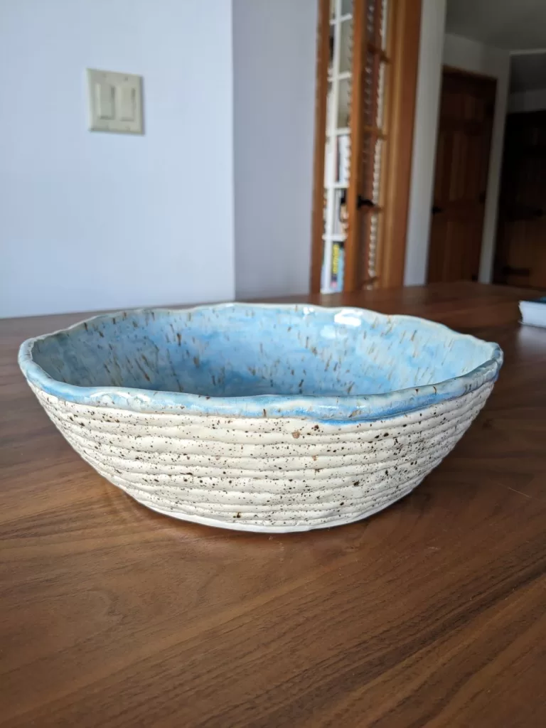 Shot of pottery coil bowl in the daylight. Turquoise glaze is gleaming.