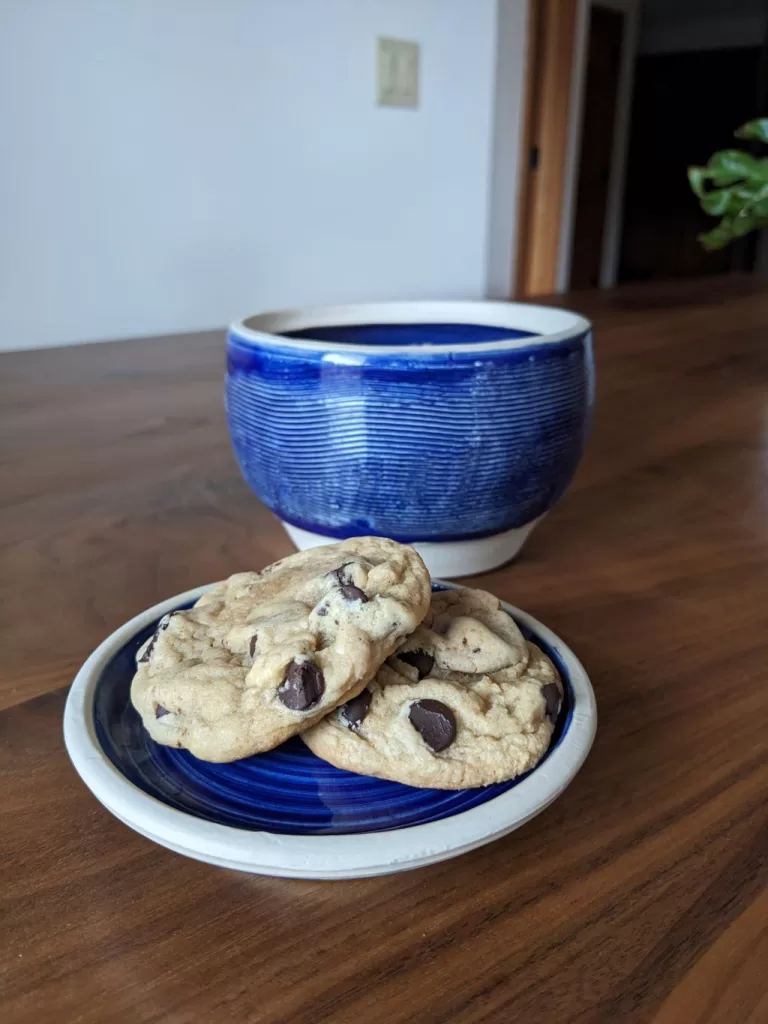 The practical pottery jar with cookies on a plate on a wooden table,