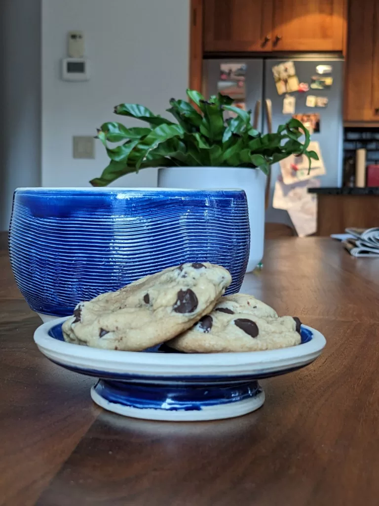 A blue pottery cookie jar feature a practical lid that can hold cookies when flipped upside down.
