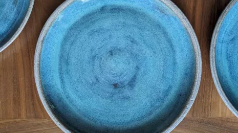 Close up of round pottery plate made with granite clay and turquoise glaze for the eating surface.