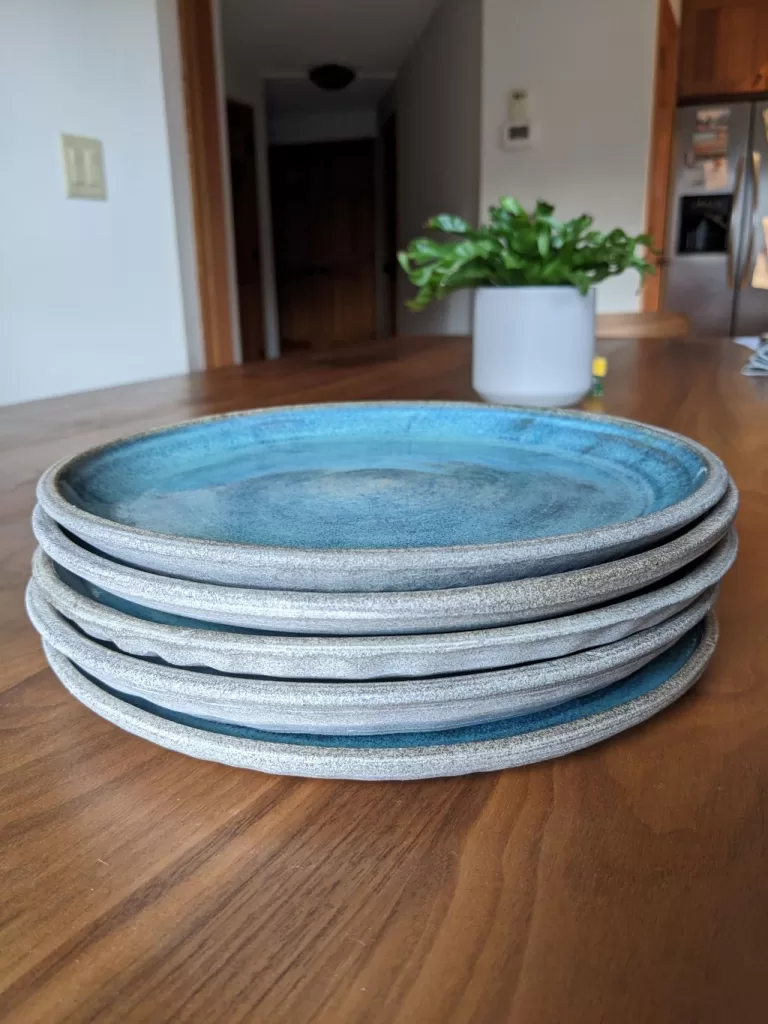 Stack of pottery dinner plates on a wooden table.