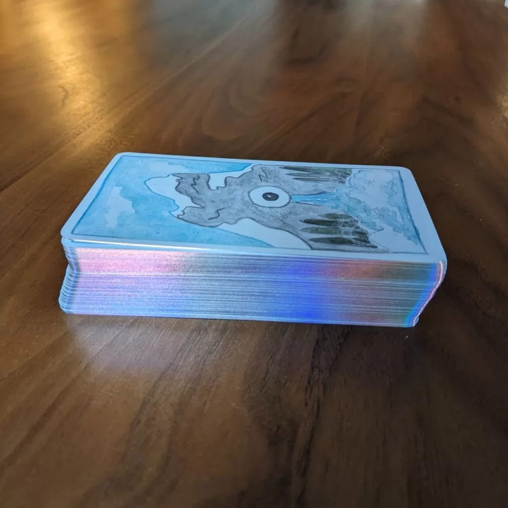 Photo of Playful Beings Tarot deck with its holographic edge shining in the sunlight.